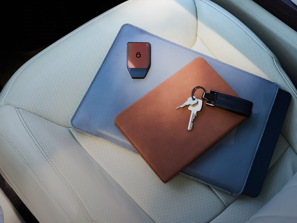 Trezor Safe 7 on notebook case with tablet and keys.